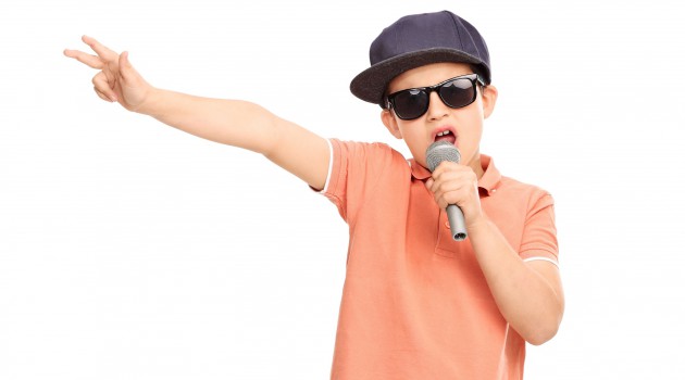 Little boy in hip hop outfit rapping on a microphone